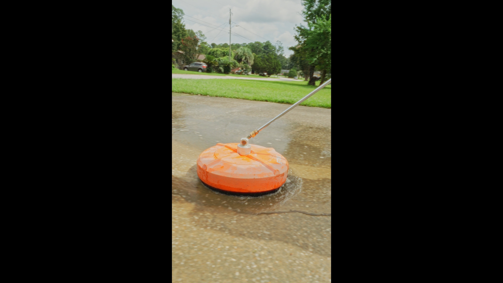 Close-up of the orange pressure-washing surface cleaner at work