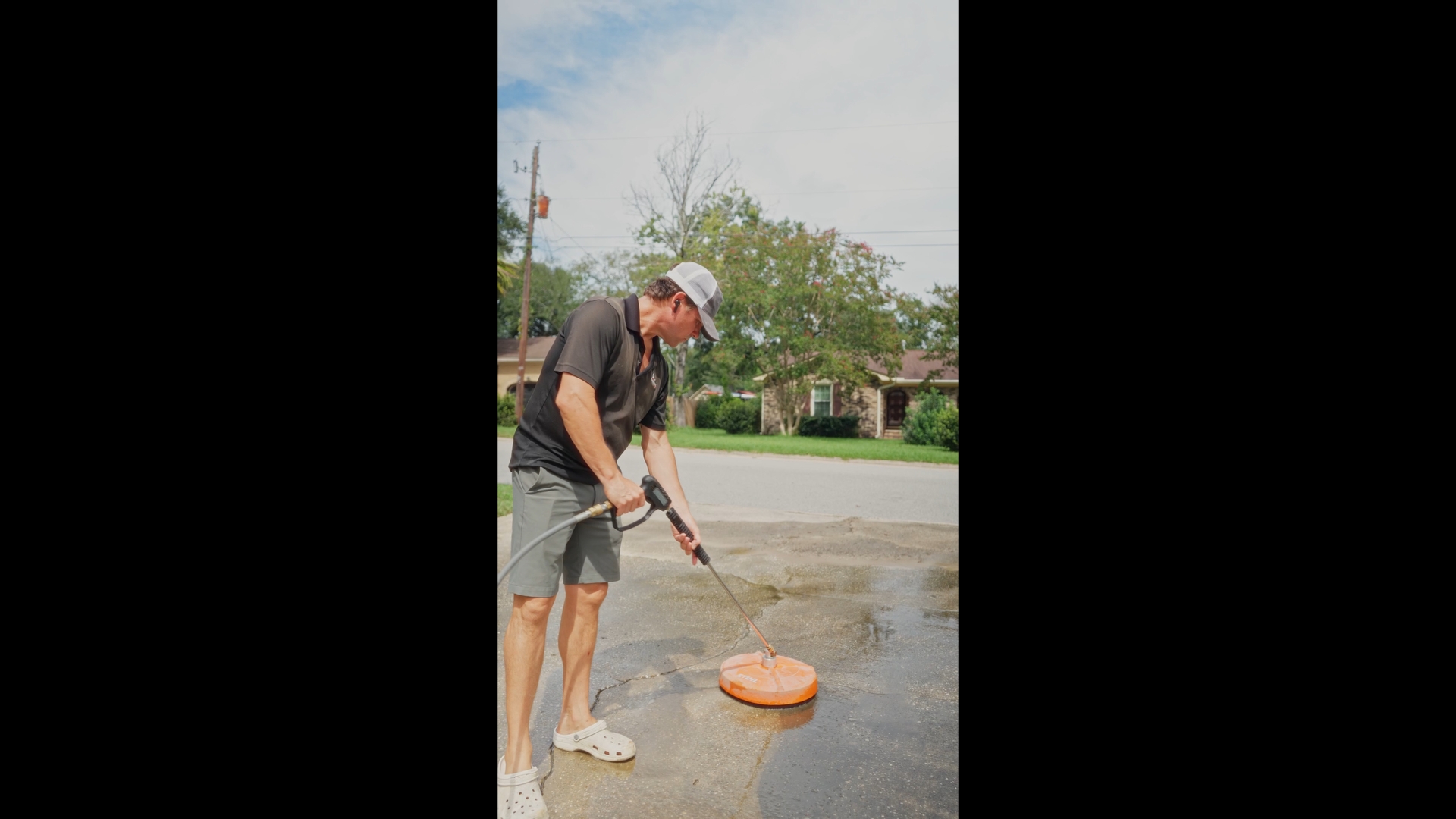 A worker pressure washing a driveway